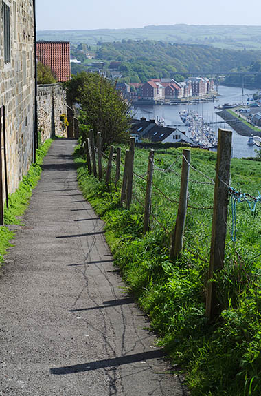 ENG: Yorkshire & Humberside Region, North Yorkshire, North Yorkshire Coast, Whitby, Abbey Steps, Paved footpath leads from top of steps down to harbor, between buildings and meadow; harbor view. [Ask for #270.148.]