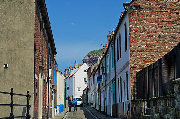ENG: Yorkshire & Humberside Region, North Yorkshire, North Yorkshire Coast, Whitby, Town Center, Fishermen's cottages line narrow Church Street, as sea cliffs loom behind [Ask for #270.189.]