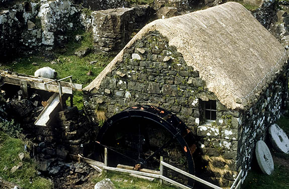 SCO: Highland Region, Skye & Lochalsh District, Isle of Skye, Inner Hebrides, Dunvegan Area, Glendale, on Loch Pooltiel, Water mill, with overshot wheel and thatched roof, beneath sea cliffs [Ask for #111.041.]