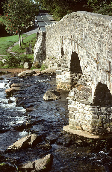 ENG: Devon , Dartmoor National Park, Central Dartmoor, Postbridge. Old coaching road (now the B3212) crossing the East Dart River on an 18th C. stone bridge [Ask for #157.068.]