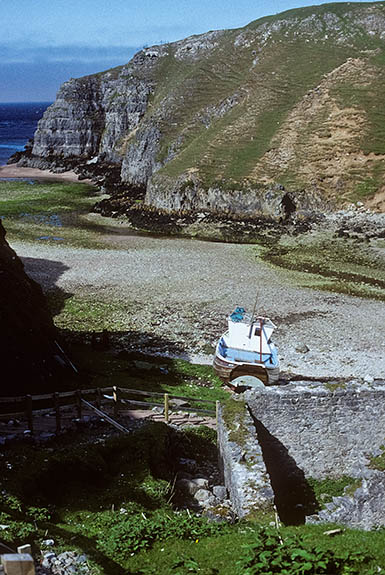 SCO: Highland Region, Sutherland District, Northern Coast, Durness, Smoo Cave, Fishing boat beneath cliffs at mouth of sea cave [Ask for #178.011.]