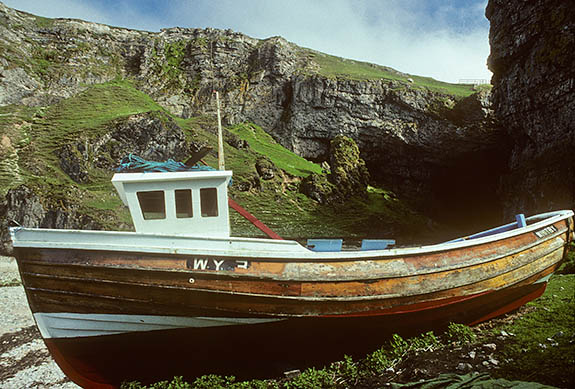 SCO: Highland Region, Sutherland District, Northern Coast, Durness, Smoo Cave, Fishing boat beneath cliffs at mouth of sea cave [Ask for #178.012.]