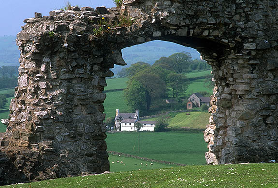 WAL: Denbighshire County, Vale of Clwyd, Denbigh, Denbigh Castle. View through a ruined arch towards a Welsh farmhouse [Ask for #246.008.]