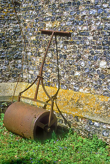 ENG: South East Region, Hampshire, The North Downs, Burghclere Area, Newtown Village, Village church (c. 1869); lawn roller leaning against flint wall. [Ask for #253.126.]