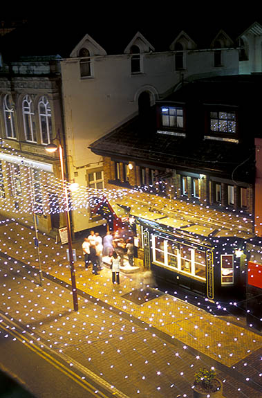 ENG: Blackpool Borough, Central City, Historic Town Center, Historic Town Center. People stand in front of a pub, Scruffy Murphys; Coronation St decorated in chandelier style lights as part of the Illuminations Festival, lighted and at night [Ask for #262.076.]