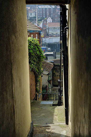 ENG: Yorkshire & Humberside Region, North Yorkshire, North Yorkshire Coast, Whitby, Town Center, Harbor view down Arguments Yard, one of many tiny passageways leading off Church Street, a pedestrianized shopping district carrying the Cleveland Way [Ask for #270.199.]