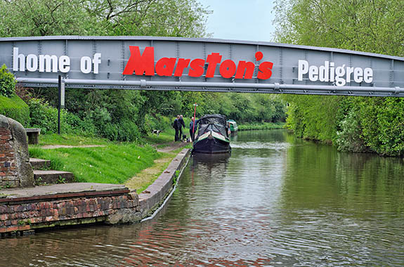 ENG: West Midlands Region, Staffordshire, The Trent Valley, Burton-on-Trent, The Trent and Mersey Canal, Industrial continuity; the canal port responsible for the Marstons and Bass brewery sites of the 1850s is still in use, overpassed by a Marstons pipeline [Ask for #270.247.]